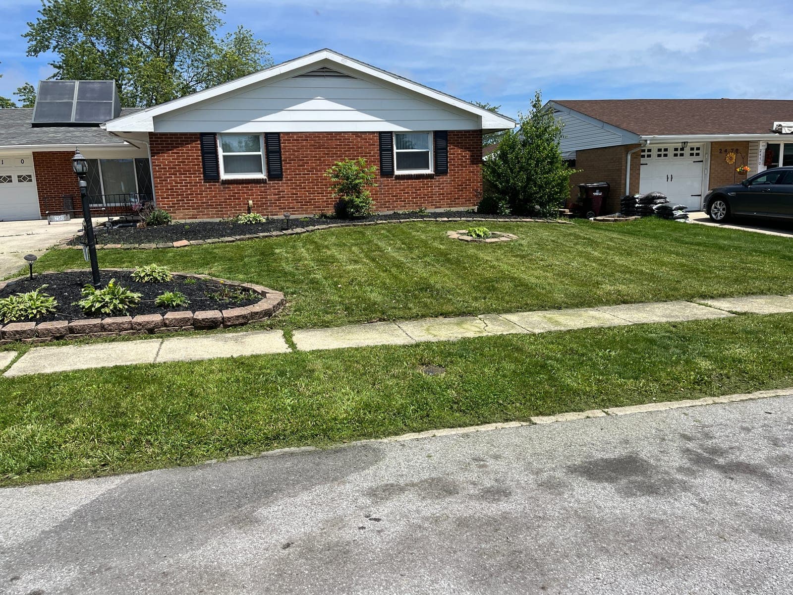 Brick ranch home with landscaped beds and a striped lawn