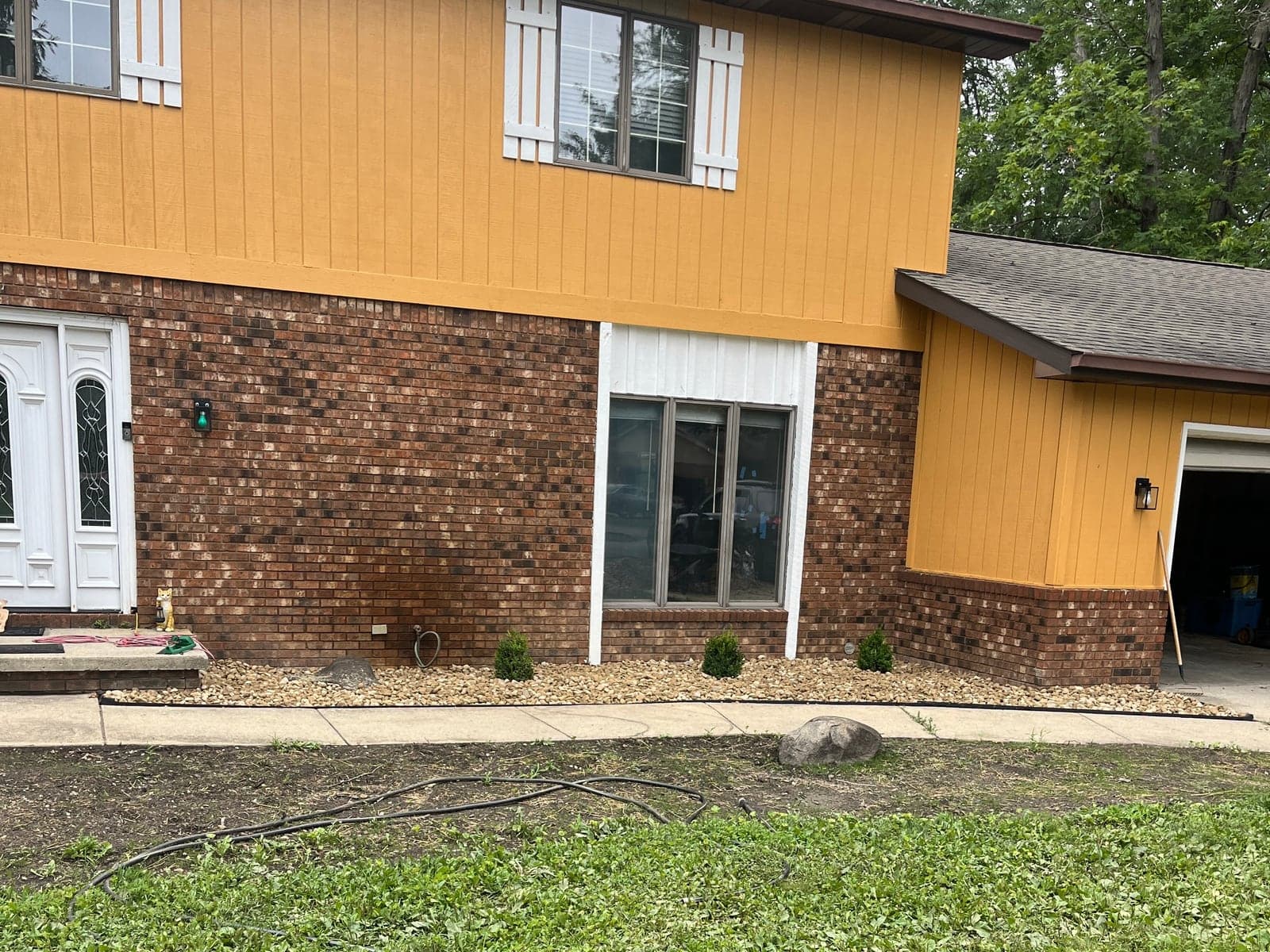 River rock bed installed along the front of a brick home